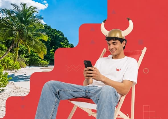 Uśmiechnięty mężczyzna w hełmie z rogami trzyma telefon i siedzi na leżaku
