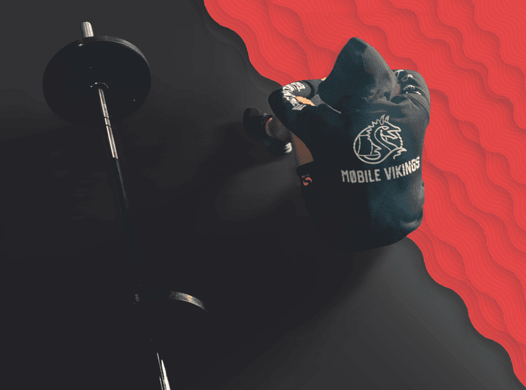 Osoba w bluzie Mobile Vikings siedzi obok sztangi, na głowie ma kaptur