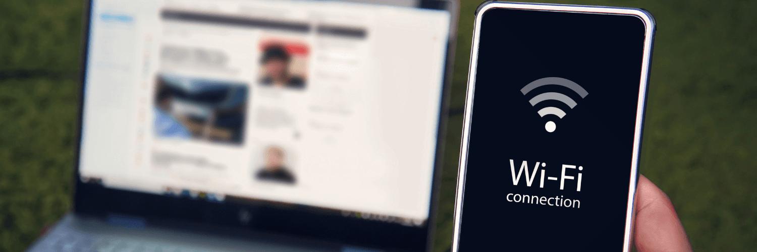 Telefon z ikoną wi-fi na ekranie oraz laptop w tle