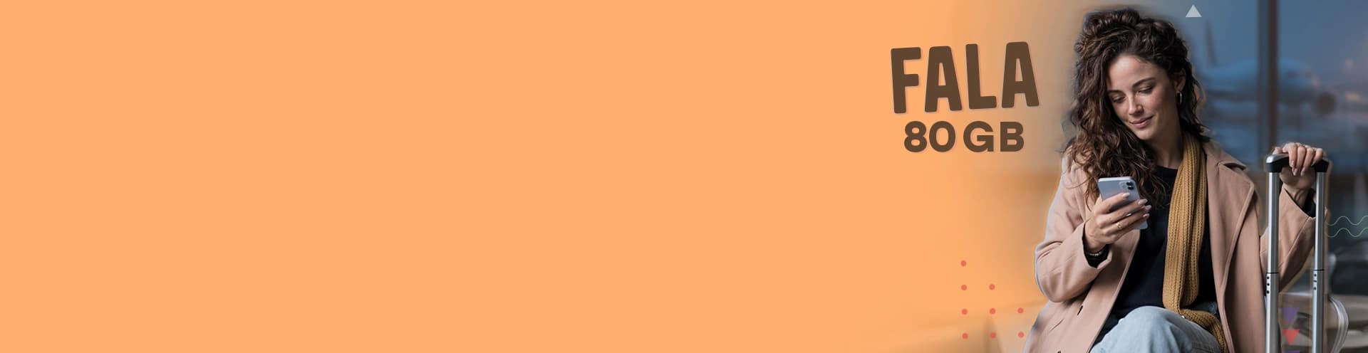 Delikatnie uśmiechnięta kobieta w płaszczu siedzi w terminalu lotniczym i spogląda na telefon trzymany jedną ręką, drugą dłoń opartą ma na wysuniętym uchwycie walizki, a w tle widać samolot stojący na pasie startowym.