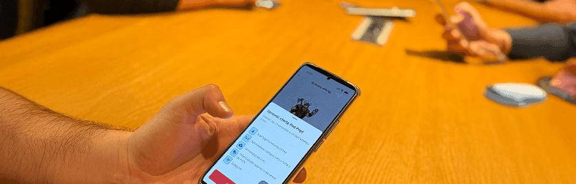 Osoba trzyma telefon z otwartą stroną forum Mobile Vikings przy stole