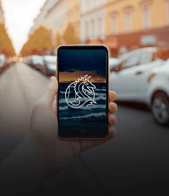 A phone held in hand, displaying the Mobile Vikings logo on the screen, with the sea and sunset in the background