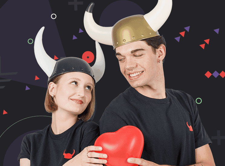 Uśmiechnięta para w hełmach Vikingów trzyma balon w kształcie serca i patrzy na siebie