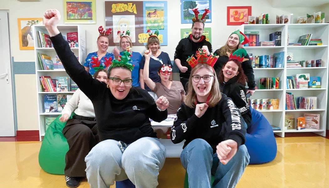 Grupa wesołych osób na tle biblioteczek