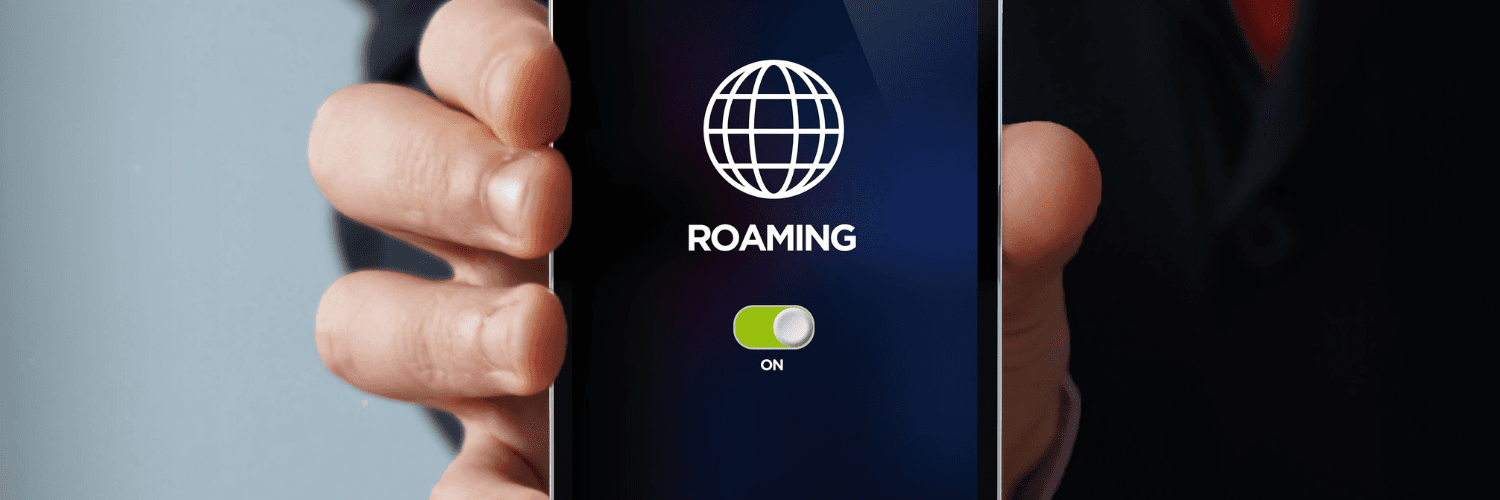 Dłoń trzymająca telefon z ikoną Roaming i sygnałem, że ten jest włączony.