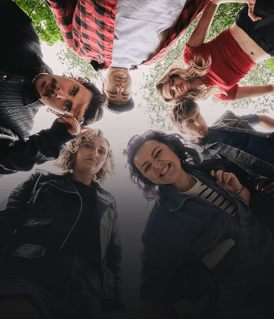 Six young people look down toward the camera; some are serious, others smiling