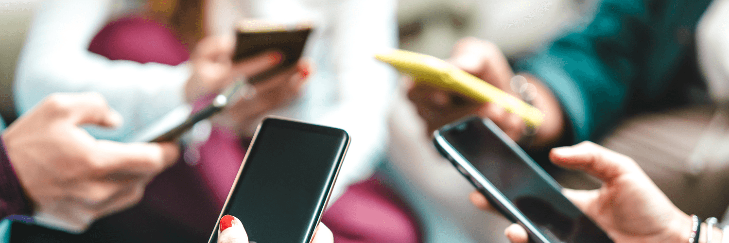 Dłonie trzymają telefony komórkowe.