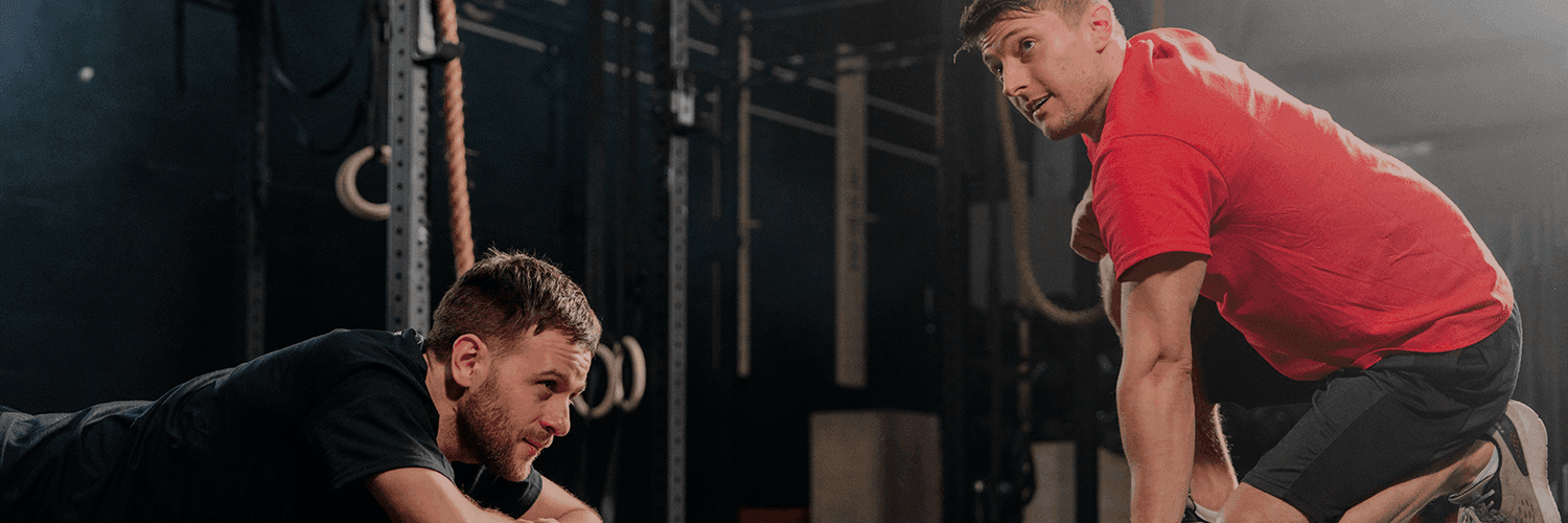 Dwóch mężczyzn w siłowni, jeden wyraźnie zmęczony leży, drugi siedzi, rozmawiają, tematem jest stereotypowe myślenie o depresji