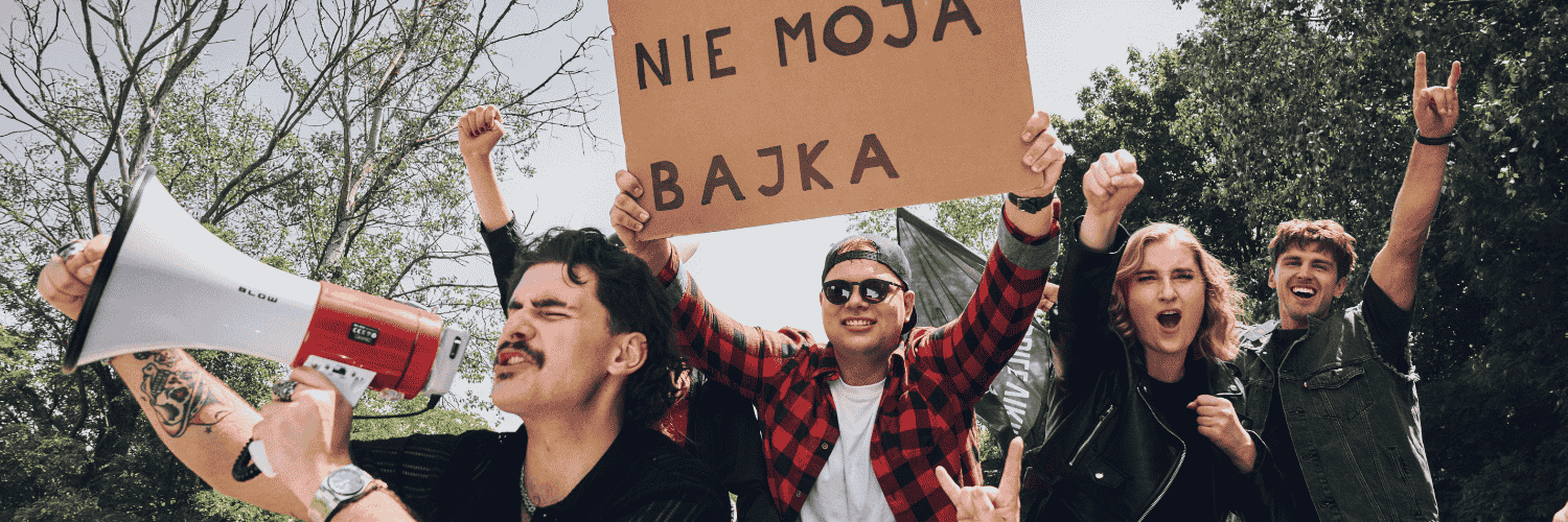 Grupa radosnych osób manifestuje radość z rozwiązania umowy z telefonią komórkową z transparentem Nie moja bajka